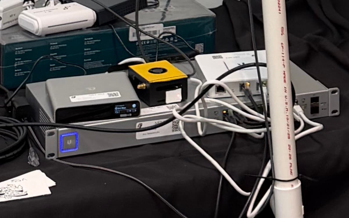 A networking switch with three smaller distinct boxes on top. One is painted yellow.