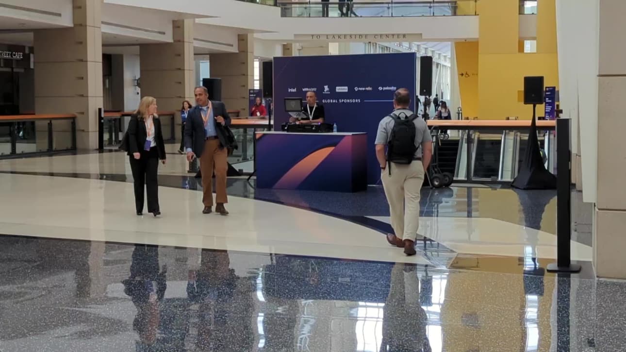 A guy is DJing alone outside the vendor hall, he is officially there to provide music. Only a few people stand chatting nearby. No one is enjoying his music.